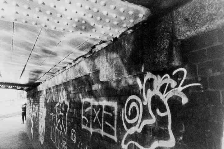 Graffiti under a canal bridge. Reflections from the waves are visible on the wall.