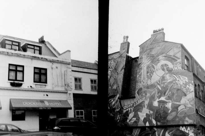 A split frame: on the left is a hotel, and on the right is a mural against fascism.